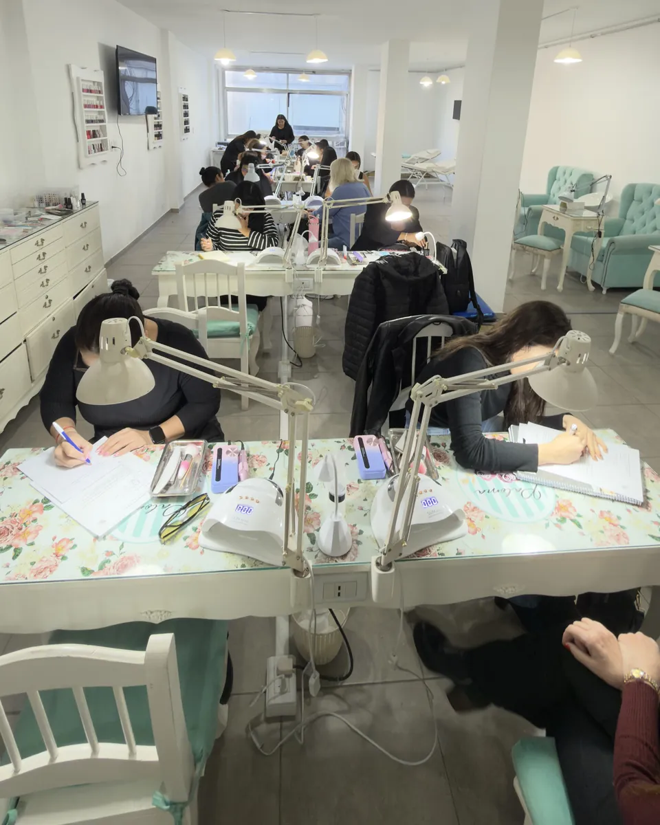 El aula de Paloma Nails School en Congreso: alumnas trabajando en las mesas de manicura con sus lámparas, y la profesora acompañando al fondo.