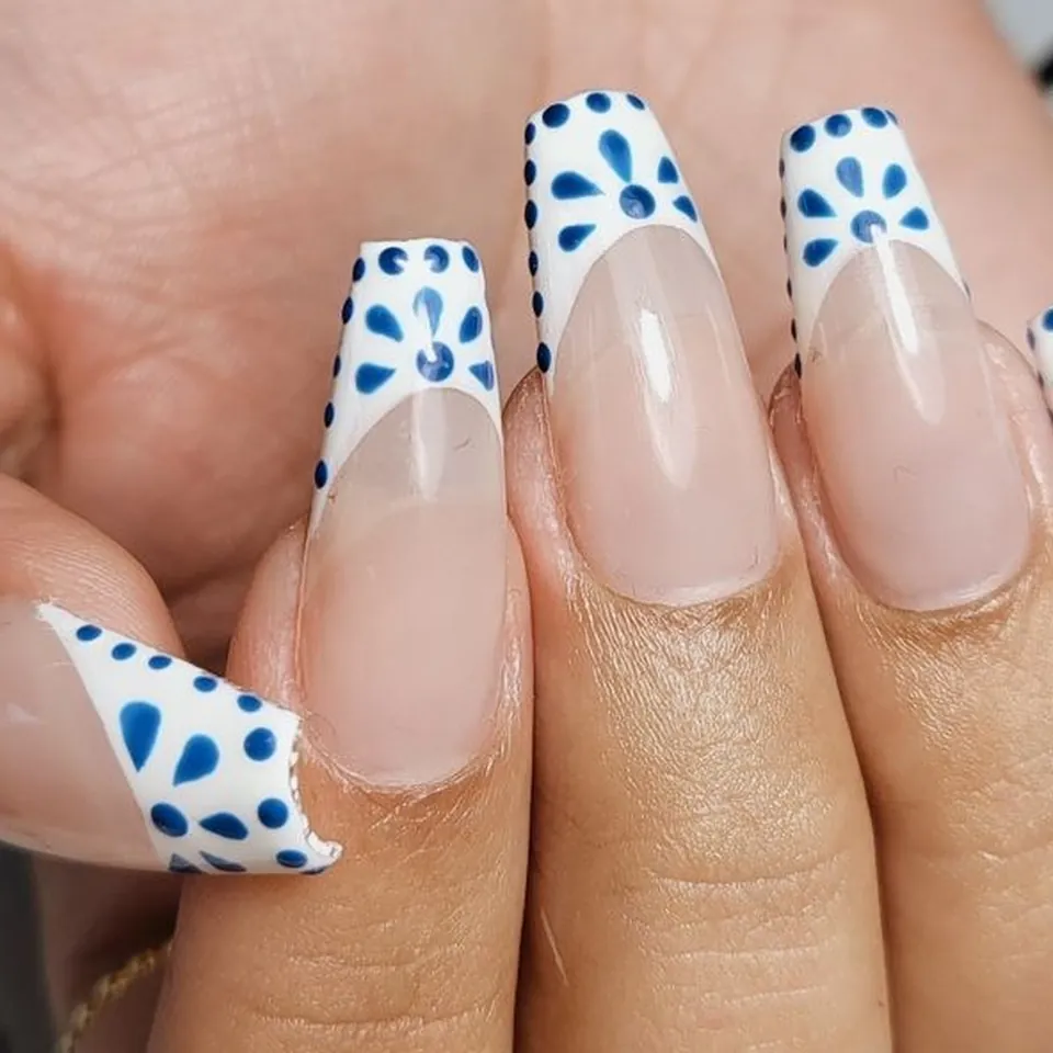Uñas bailarina con francesa blanca y puntos azules pintados a mano, estilo azulejo.