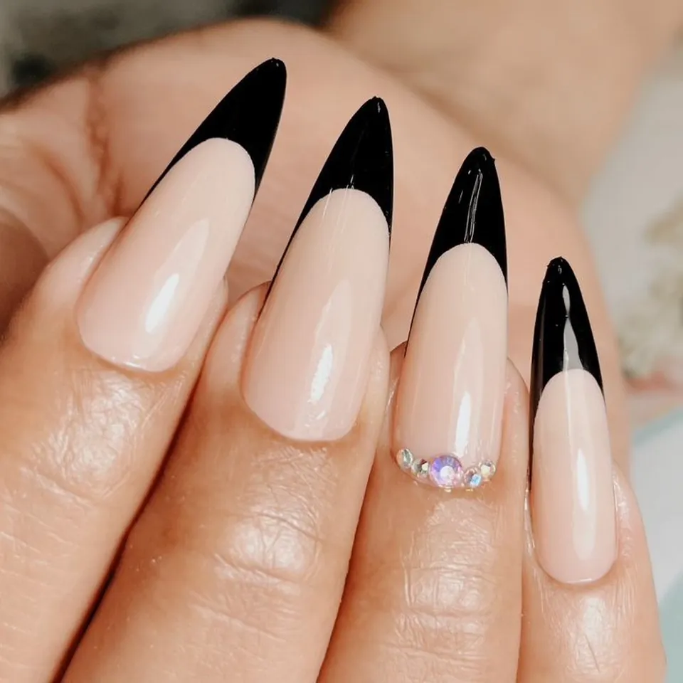Uñas stiletto en nude con francesa negra y piedras sobre la uña del anular.