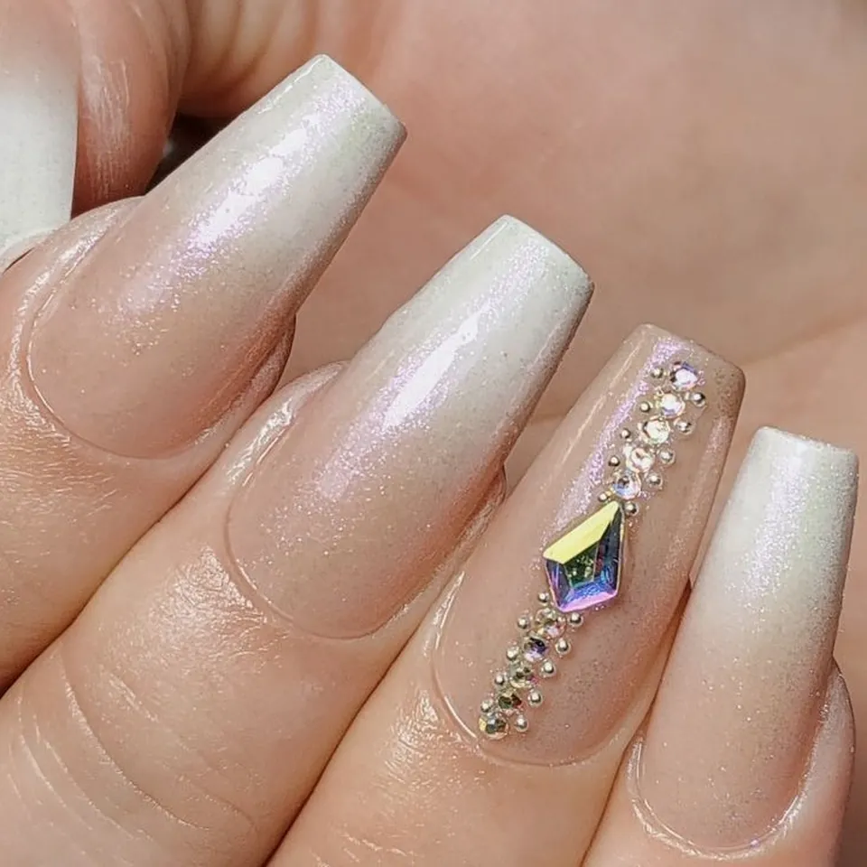 Uñas bailarina en degradé blanco perlado, con piedra y caviar plateado sobre el dedo mayor.